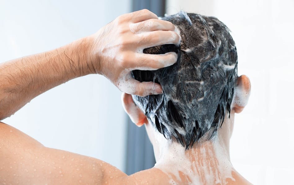 Mann wäscht sich mit Shampoo die Haare